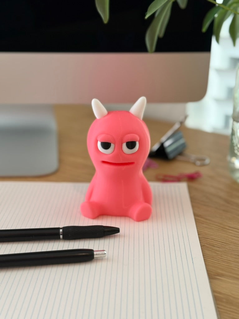 small 3D printed figurine sitting on a desk next to a computer"