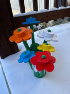 Colorful plastic flower bouquets made of interlocking bricks on a snowy surface.