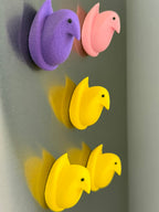 Colorful duck-shaped magnets on fridge.