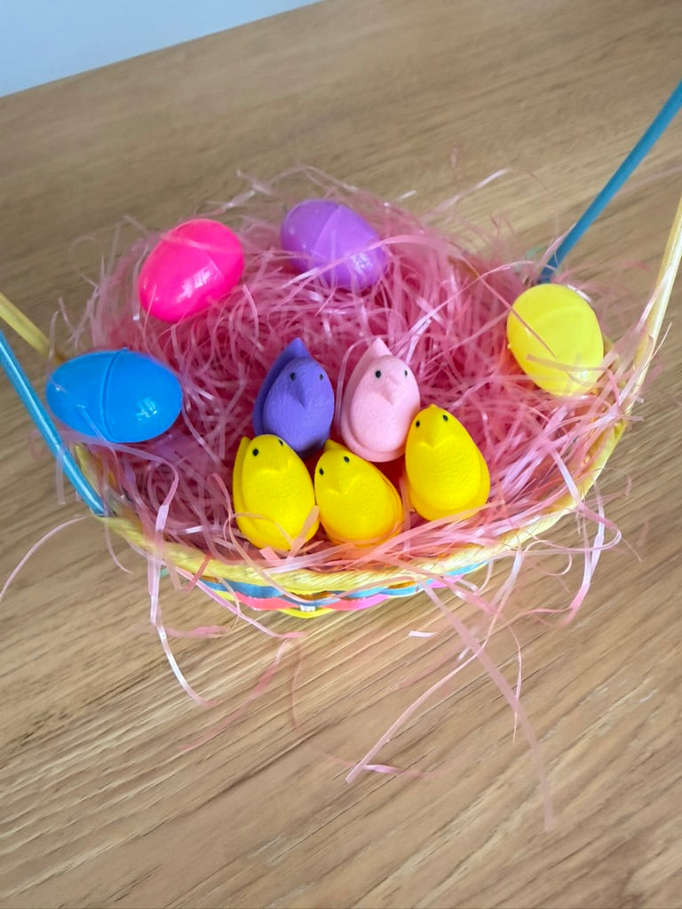 Colorful plastic Easter eggs in a nest on a wooden surface