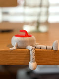 Small gray curling stone buddy with a red lid on a wooden surface