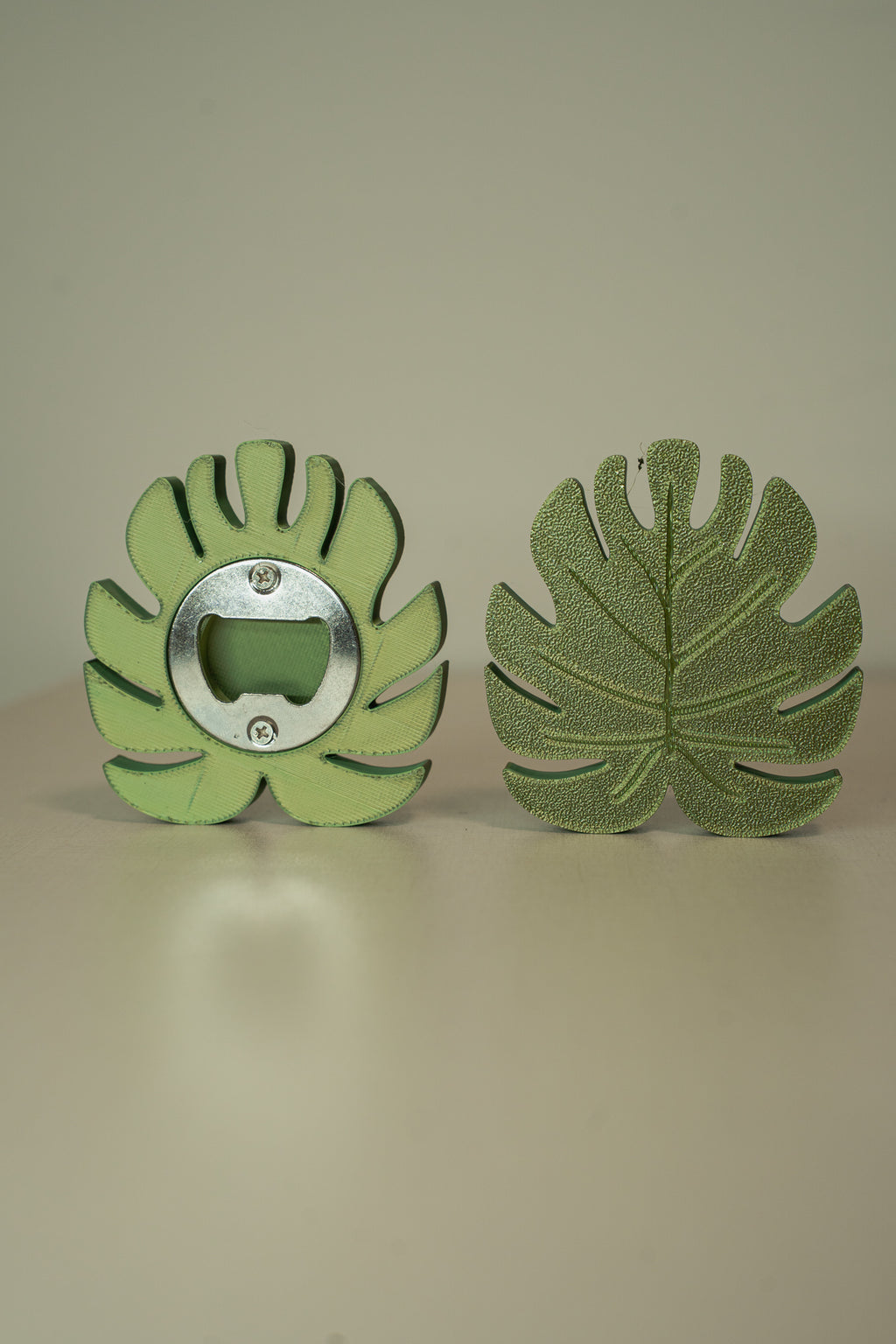 Green leaf-shaped bottle opener on a beige background
