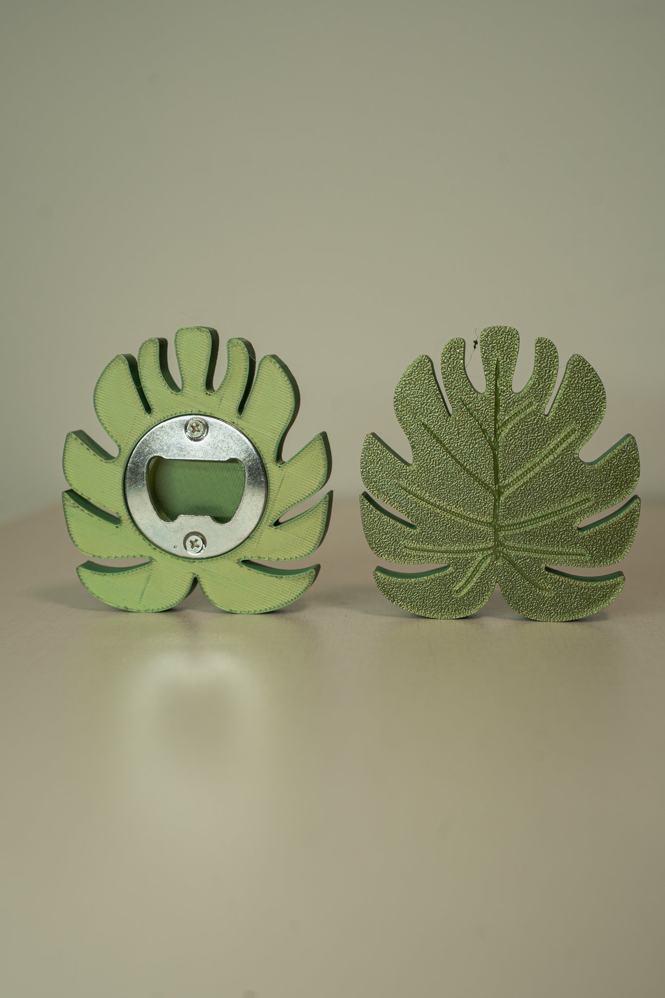 Green leaf-shaped bottle opener on a beige background