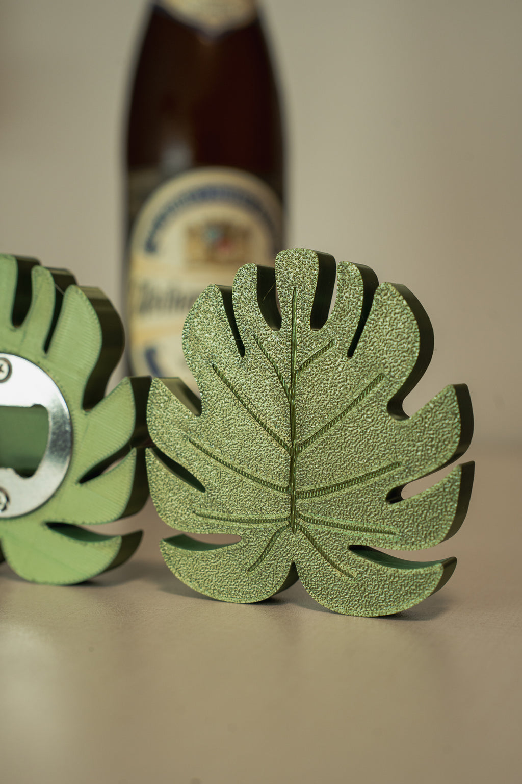 Green leaf-shaped bottle opener with a beer bottle in the background