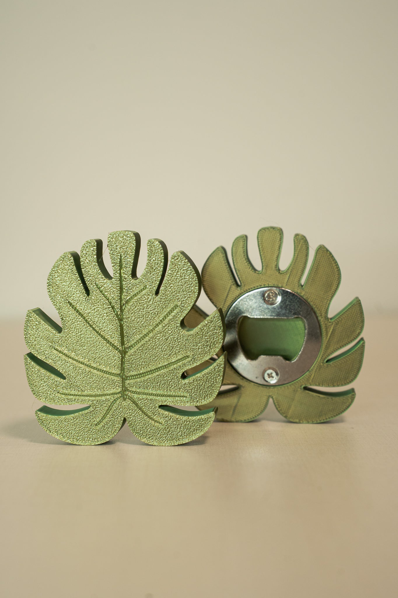 Green leaf-shaped bottle opener on a beige background