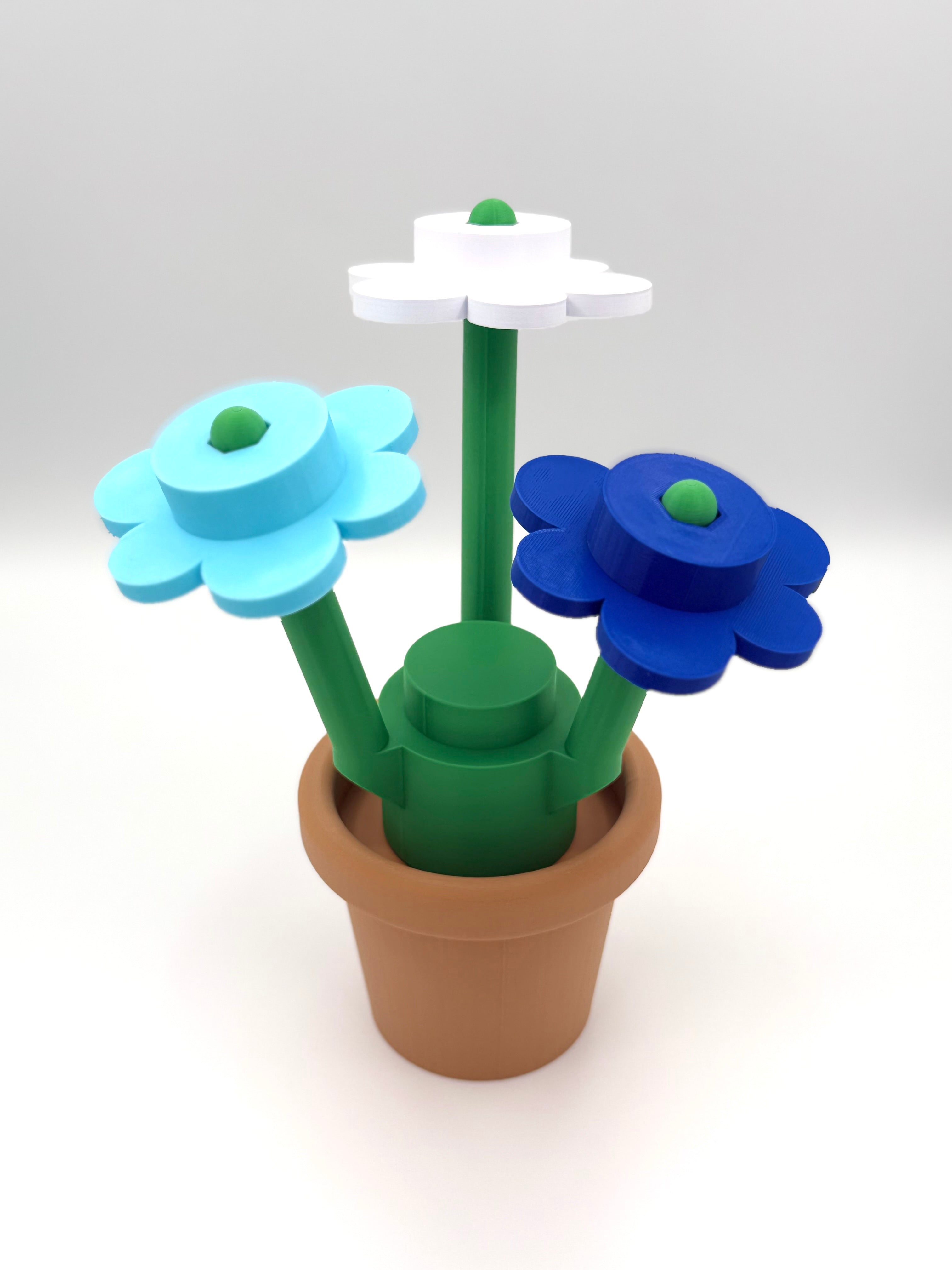 Plastic flower pot with blue and green flowers on a white background