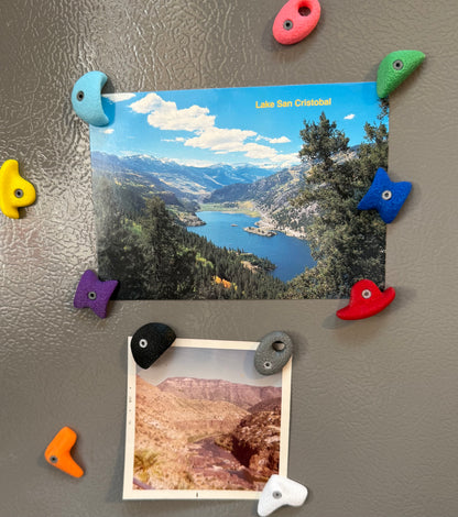 Colorful magnetic rock bouldering photo holders on a refrigerator with scenic photos attached.