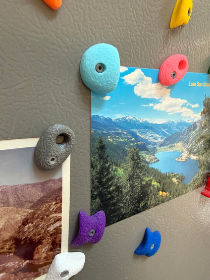 Colorful magnetic rock bouldering photo holders on a refrigerator with scenic photos attached.