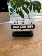 Weekly pill organizer on a wooden surface with a plant in the background