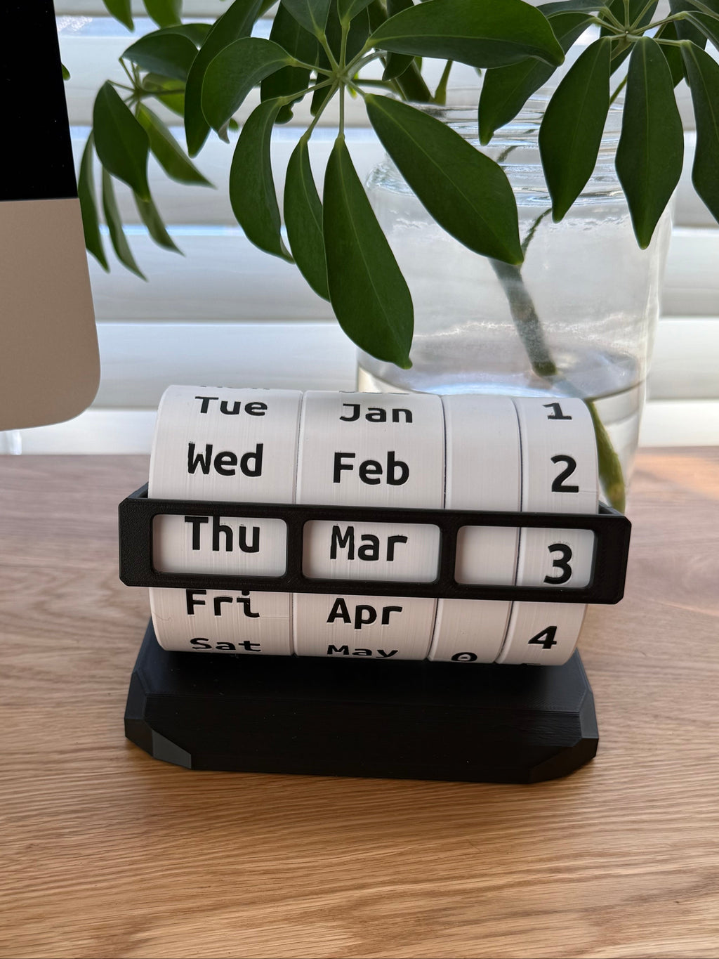 Calendar roll on a wooden surface with a plant in the background