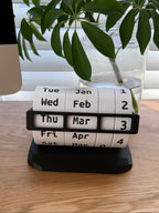 Calendar roll on a wooden surface with a plant in the background