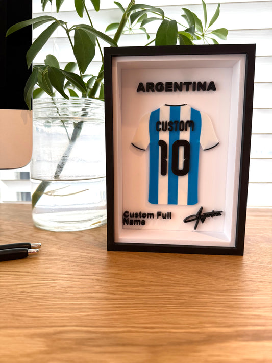 Framed Argentina soccer jersey with customizable name and number on a wooden surface.