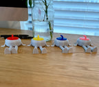Four small flexi curling stone buddies with colored heads on a wooden surface.