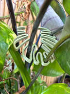 Light green spiral plant support on a leafy green background